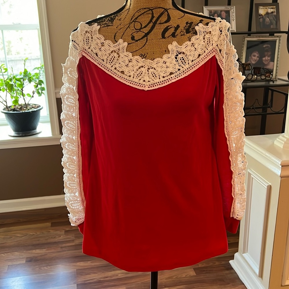 Red top with white lace around neck and down sleeves
